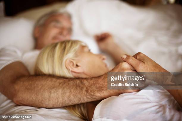mature couple embracing in bed - man and woman cuddling in bed stock-fotos und bilder