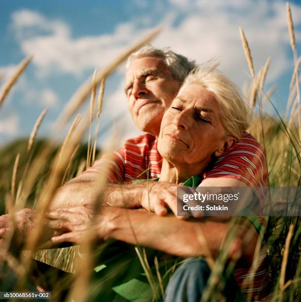 couple embracing in long grass - tranquil scene couple stock pictures, royalty-free photos & images