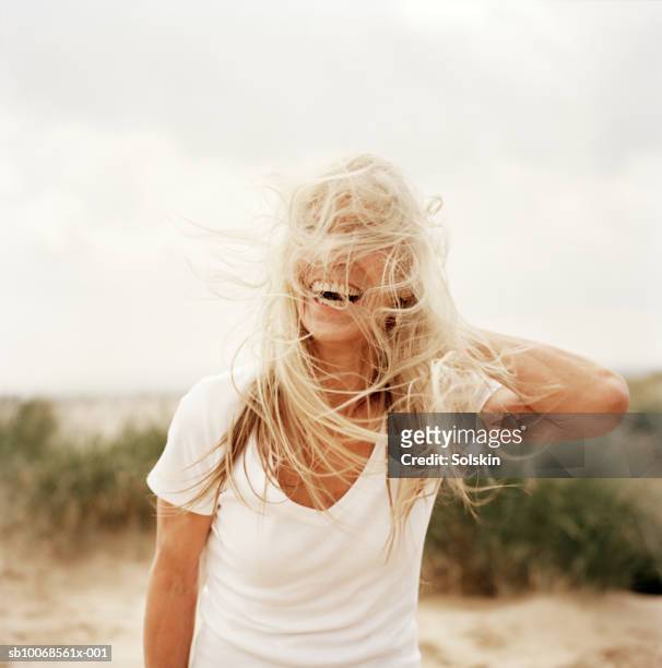 woman with windswept hair on beach - haar stockfoto's en -beelden