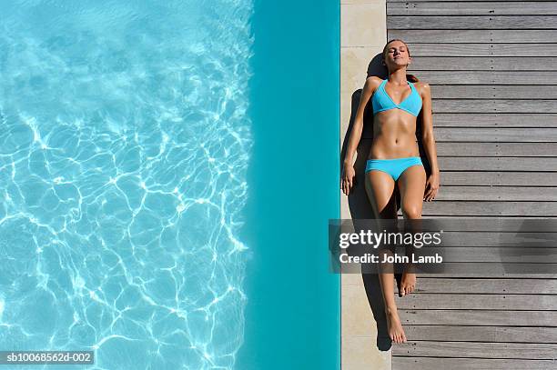 young woman sunbathing on at poolside, view from above - women by pool stock-fotos und bilder