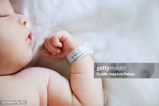 baby boy (9-12 months) sleeping with hospital bracelet on wrist, close-up - identiteit stockfoto's en -beelden