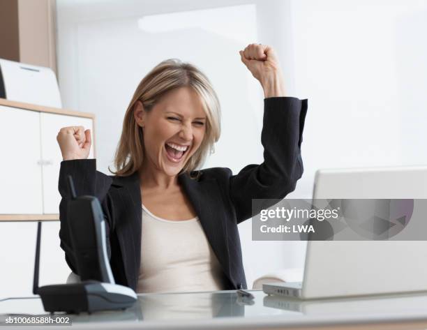 businesswoman using laptop, cheering - blonde cheering stock-fotos und bilder