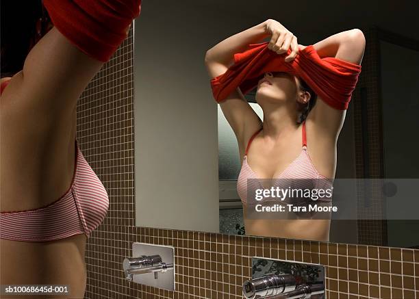 woman undressing in front of mirror in bathroom - semi dress stock pictures, royalty-free photos & images