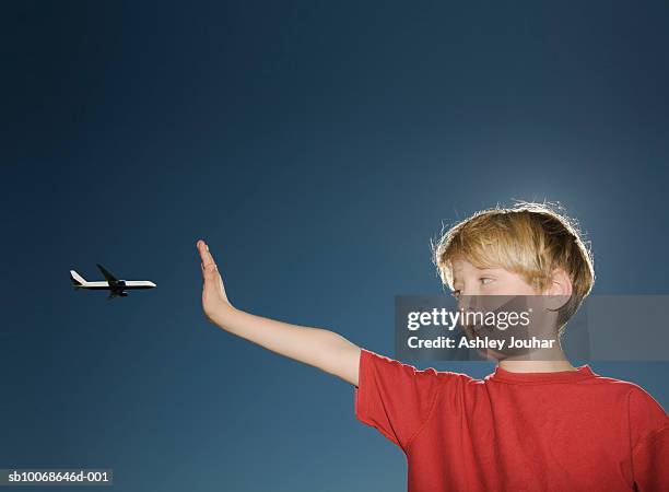 boy (6-7) stopping airplane against sky - perspectiva forzada fotografías e imágenes de stock