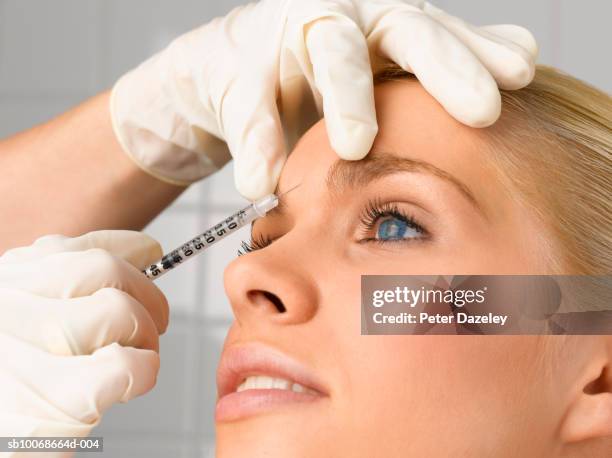 person injecting young woman's forehead with small syringe, close up, side view, studio shot - beauty portrait studio shot stock pictures, royalty-free photos & images