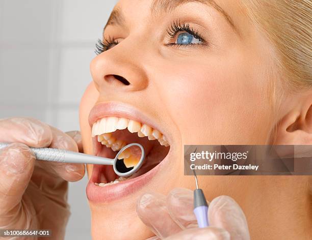 dentist holding dental instruments in young woman's mouth, close up, studio shot - plaque remover stock pictures, royalty-free photos & images