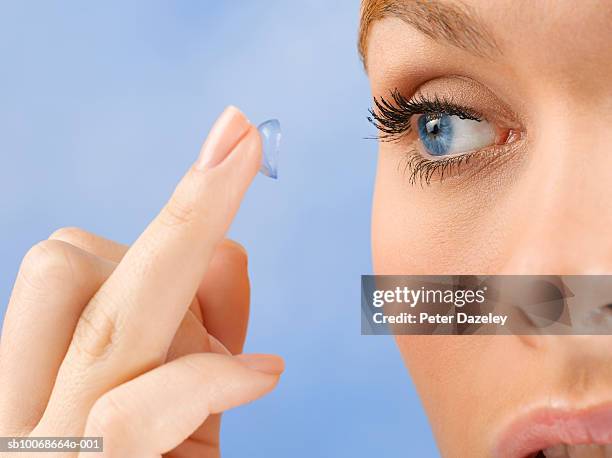 young woman holding contact lens on fingertip, close up, studio shot - lente a contatto foto e immagini stock