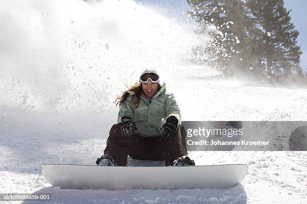 young woman sitting on slope wearing snowboard, portrait - snowboarding stockfoto's en -beelden