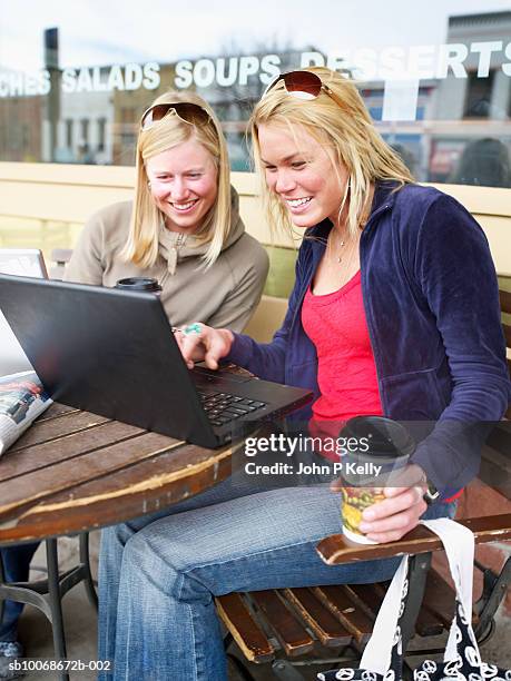 two young woman in caft using laptop, smiling - caft stock pictures, royalty-free photos & images