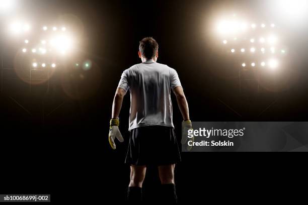 goalkeeper looking at stadium light, rear view - fußballspieler stock-fotos und bilder