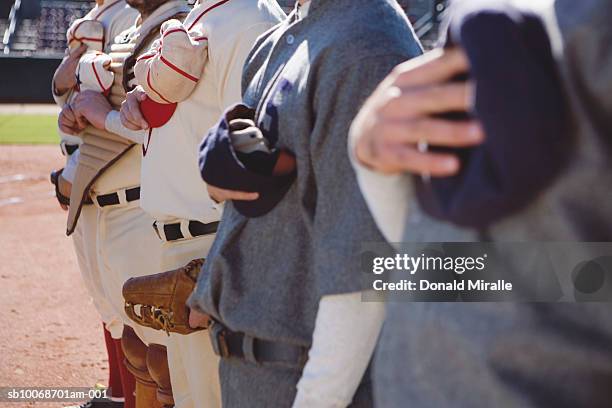 retro-style baseball players with caps over hearts for national anthem - national anthem stock pictures, royalty-free photos & images