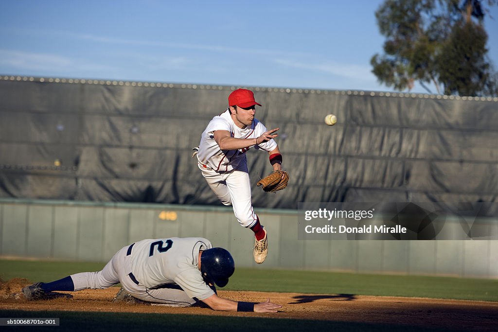 USA, California, San Bernardino, baseball runner sliding for base and baseman leaping for catch