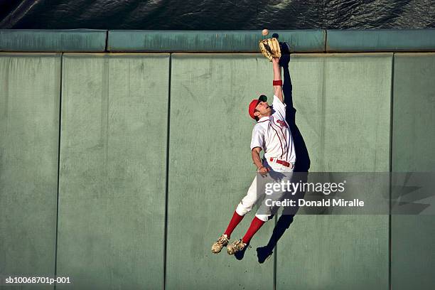 usa, california, san bernardino, baseball player making leaping catch at wall - gevangenis stockfoto's en -beelden
