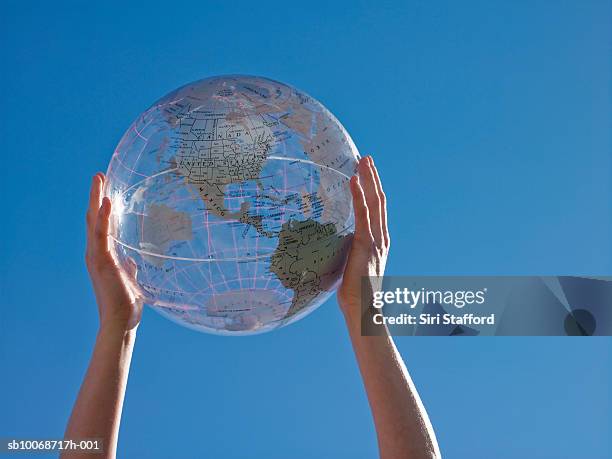 woman holding transparent globe, low angle view - frau globus stock-fotos und bilder