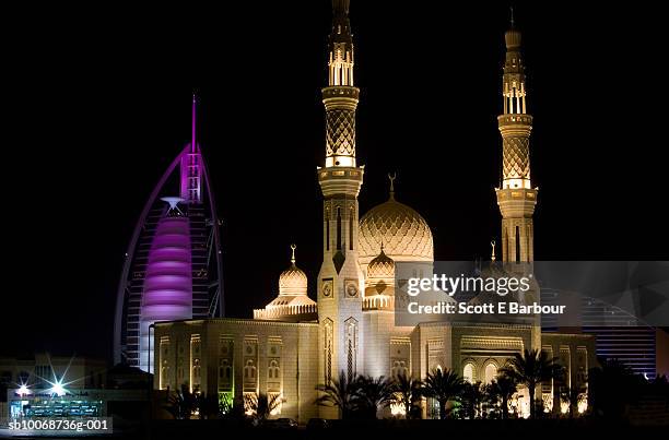 united arab emirates, dubai, jumeirah, burj al arab hotel and jumeirah beach hotel behind a mosque at night - burj al arab night stockfoto's en -beelden