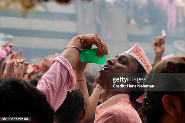 man pouring water into another man's mouth during celebration of lord shri ganesha - bracelet festival photos et images de collection