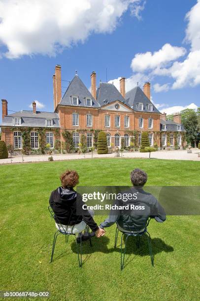 france, normany, couple in lawn chairs in front of chateau - normandy stock pictures, royalty-free photos & images