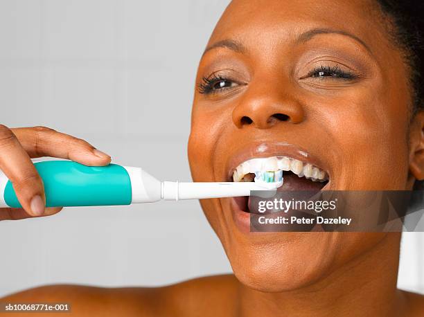 woman lcleaning teeth with electric toothbrush, close up, studio shot - elektrische zahnbürste stock-fotos und bilder