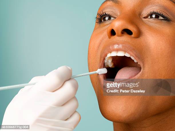 person putting dna test swab into woman's mouth, close up, studio shot - cotton swab ストックフォトと画像