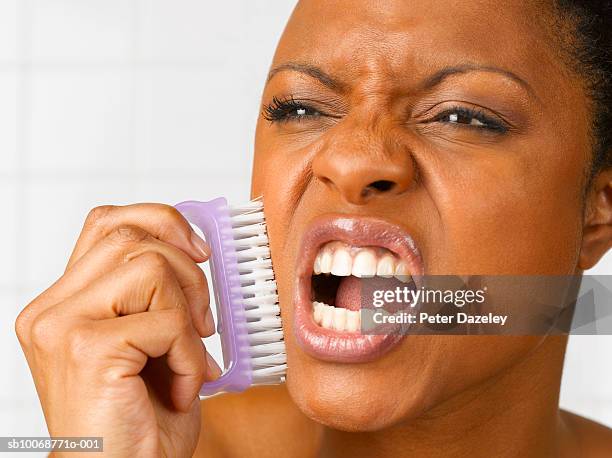 woman holding nailbrush to cheek, close up, studio shot - exfoliation face stock pictures, royalty-free photos & images