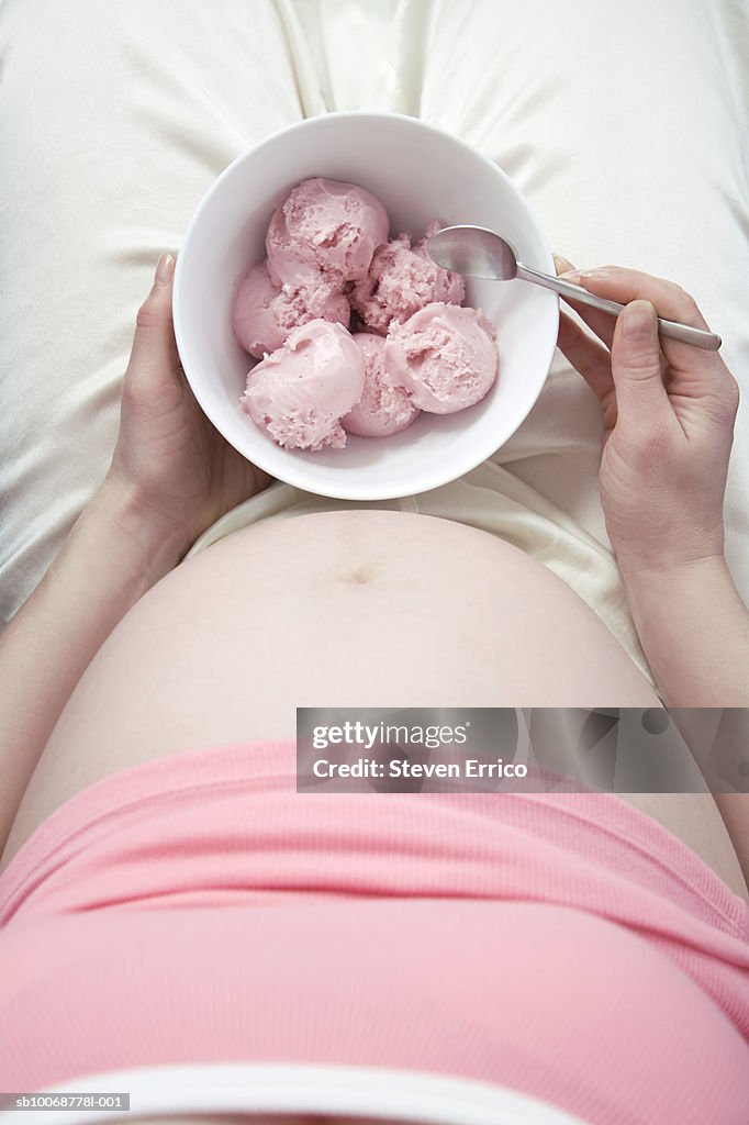 Pregnant woman sitting with holding bowl of ice-cream
