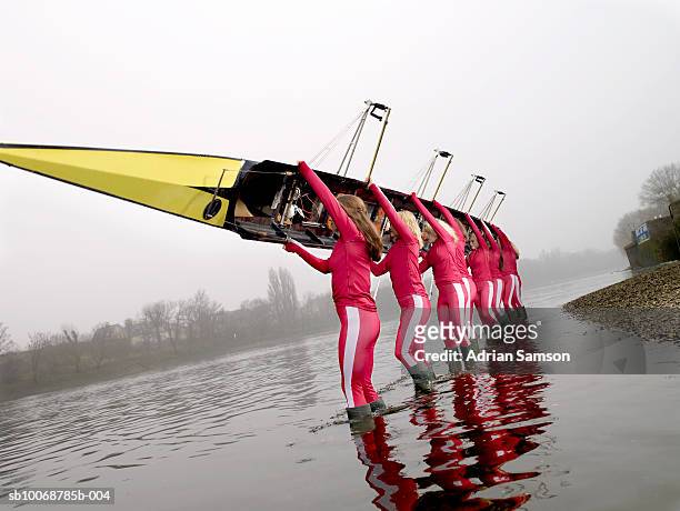 female rowers standing in lake carrying eight person-scull - woman carrying stock pictures, royalty-free photos & images