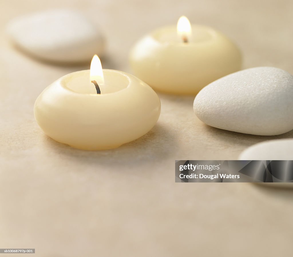 Lit candles and pebbles, close-up