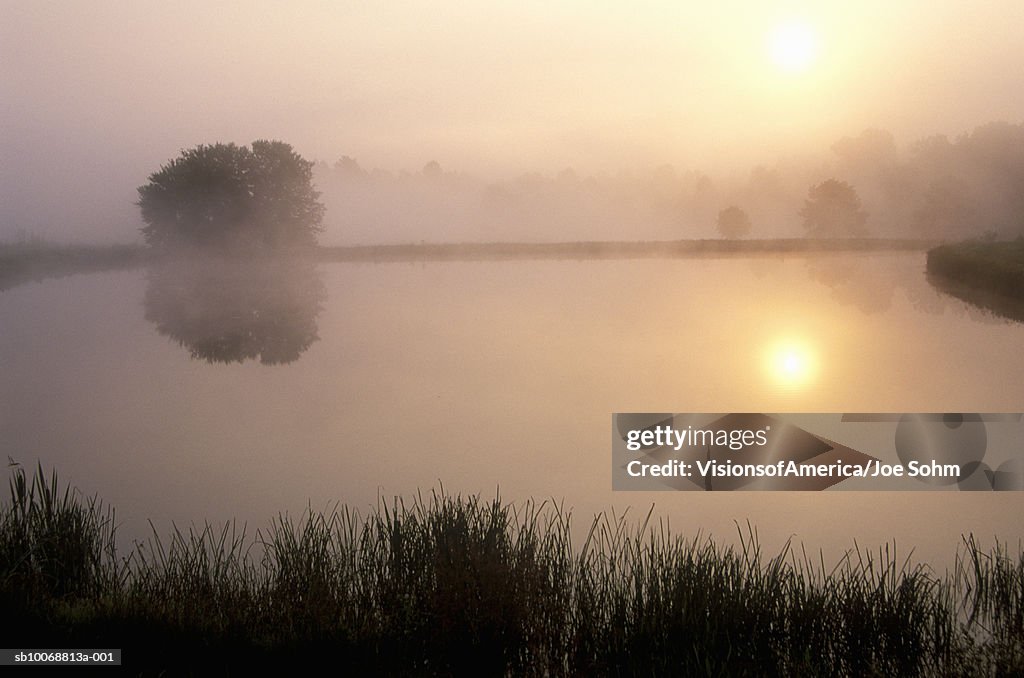 Sunrise reflecting in fog covered lake