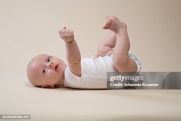 boy (2-5 months) laying on back, studio shot - soltanto un neonato maschio foto e immagini stock