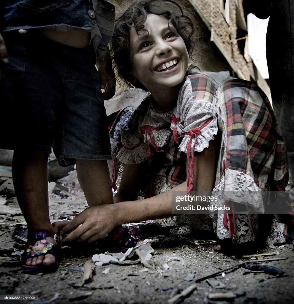 Girl (8-9) fixing sandal of child