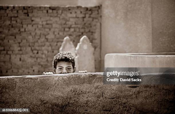 boy (8-9) peeking from behind wall, portrait, high section - north africa photos et images de collection