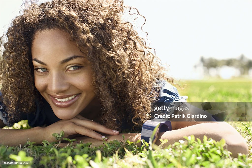 Young woman lying on grass, smiling