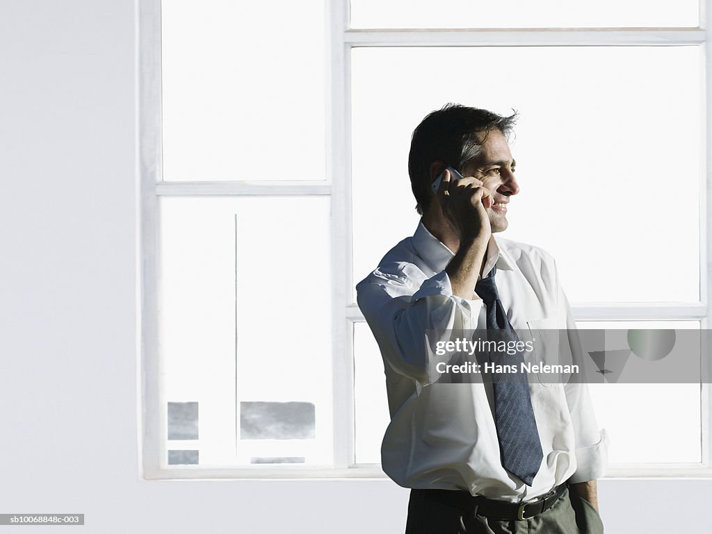 Businessman using mobile phone, smiling