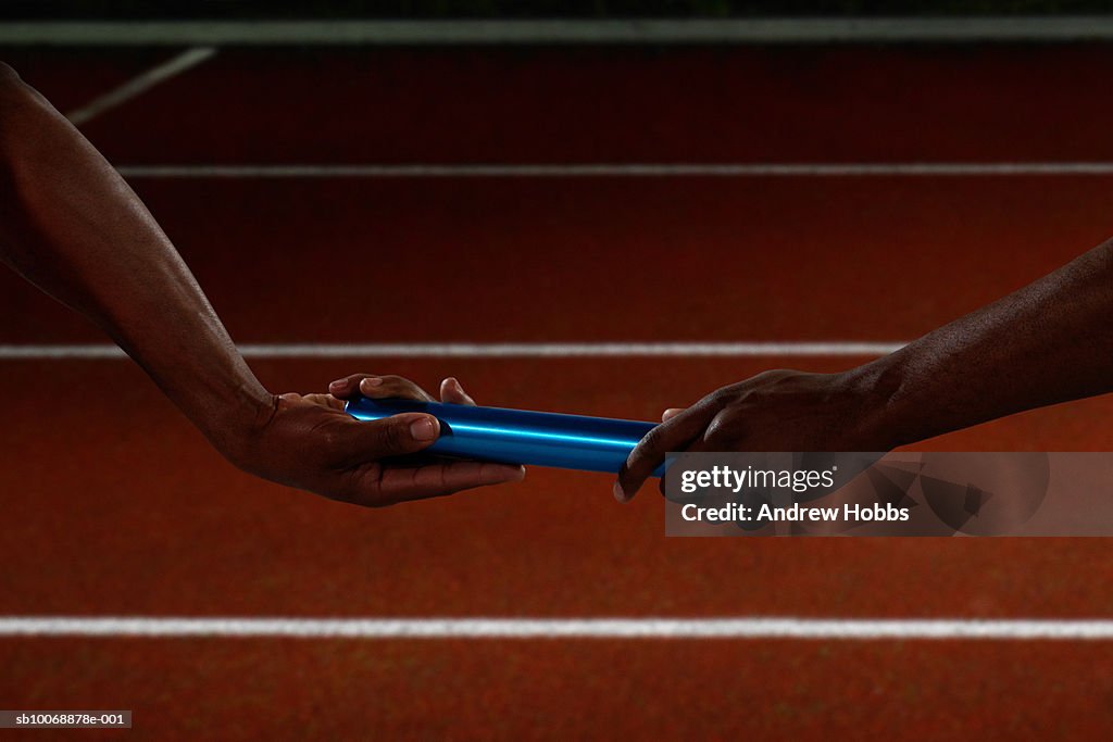 Athletes handing off baton, close up of hands