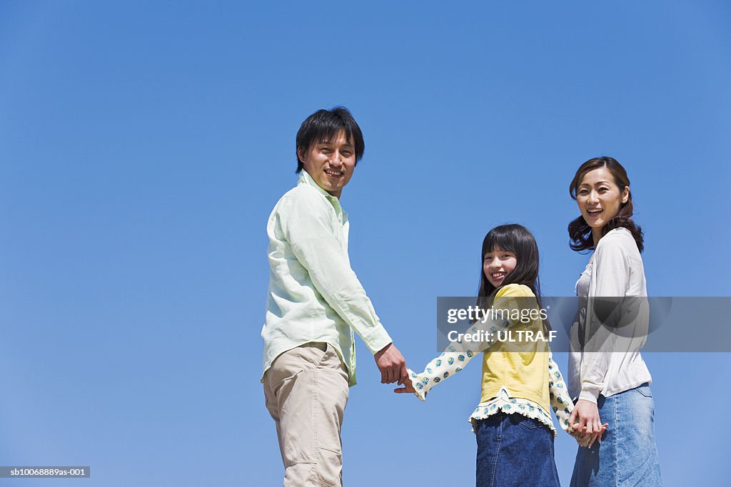 Portrait of family including young girl against clear blue sky