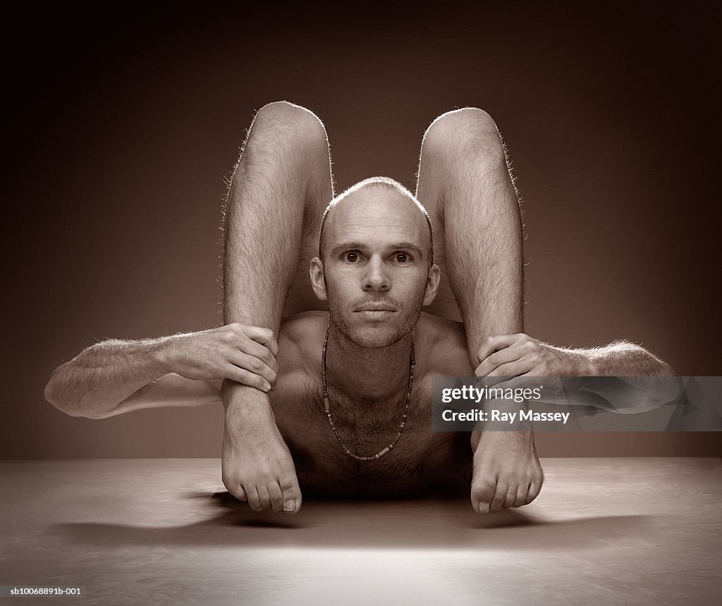 Male Contortionist holding ankles, portrait