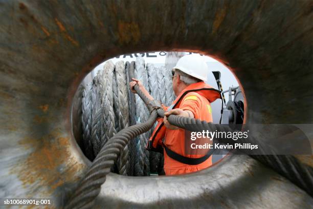 tugboat sailor feeding heavy ships mooring rope through ships bow - aangemeerd stockfoto's en -beelden