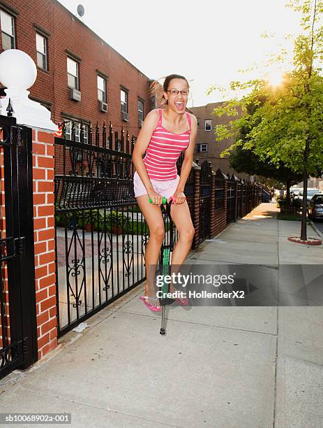 teenage girl (14-15) on pogo stick on sidewalk - pogo stick stock pictures, royalty-free photos & images