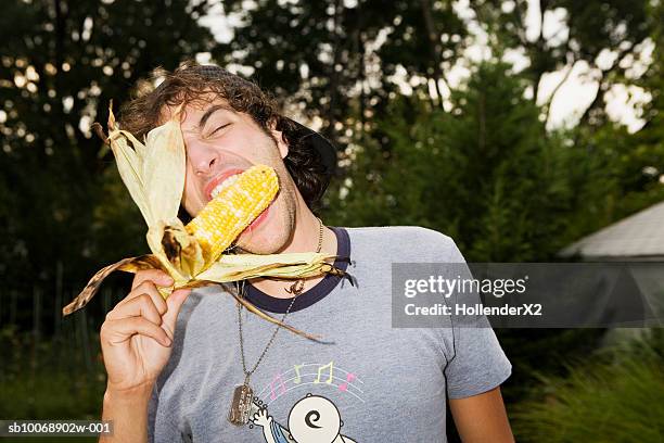 man biting raw corn in garden - biting ストックフォトと画像