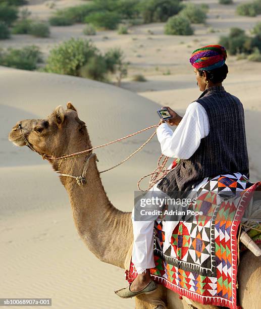 man sitting on camel, using satellite navigation device - automotive navigation system stock pictures, royalty-free photos & images