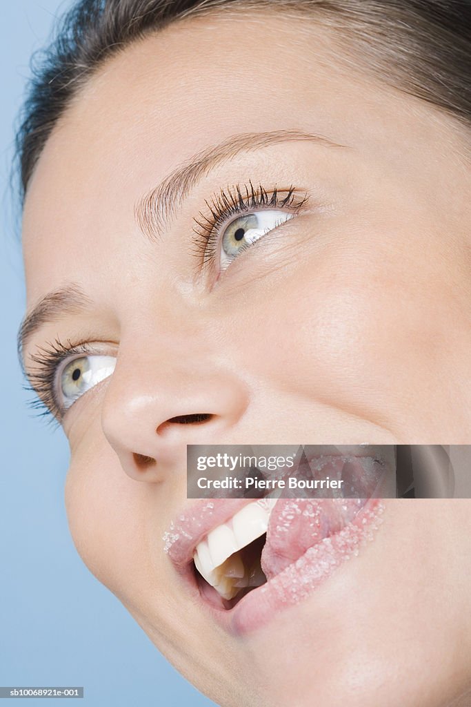 Young woman licking sugar of lips, close-up, studio shot