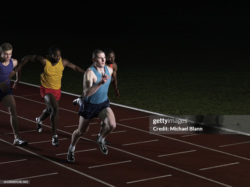 Athletes running on race track, trying to stop one athlete from winning