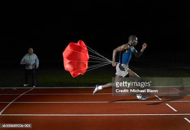 athlete running on race track with parachute on back - running coach stock pictures, royalty-free photos & images