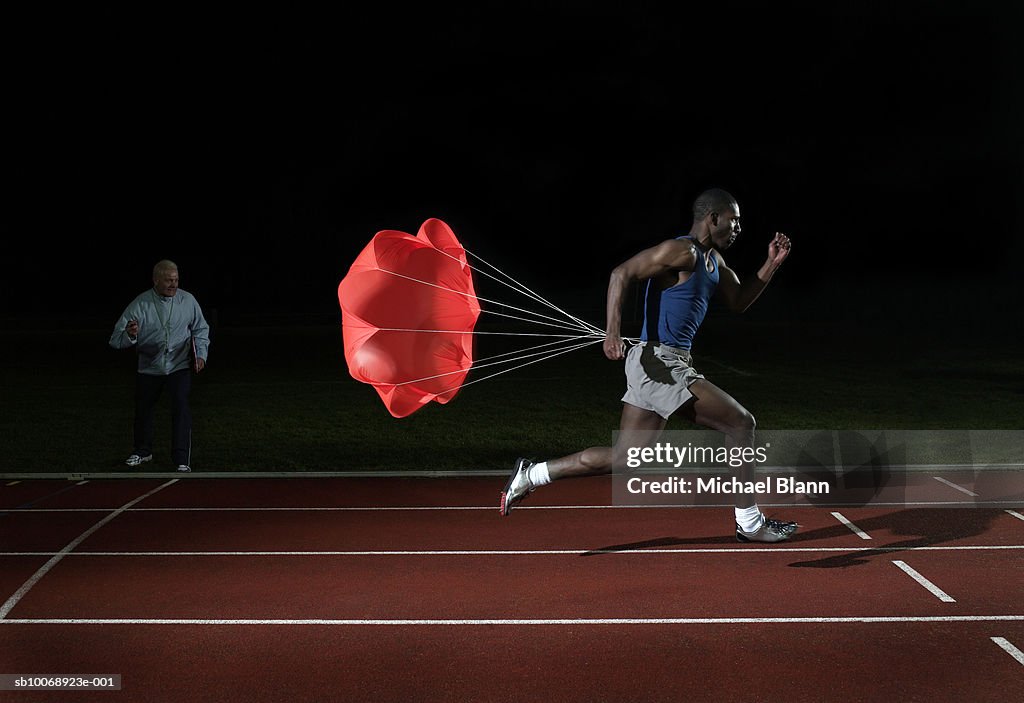 Athlete running on race track with parachute on back