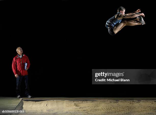 long jump athlete jumping, coach watching - mens long jump - fotografias e filmes do acervo