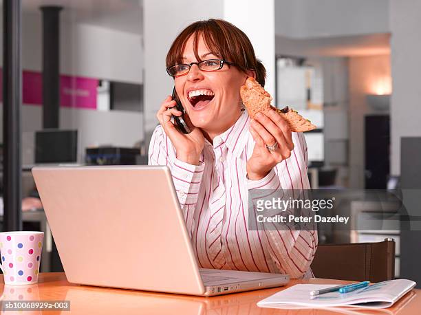 woman sitting at table with laptop, using mobile phone and  eating - mouth open eating stock pictures, royalty-free photos & images
