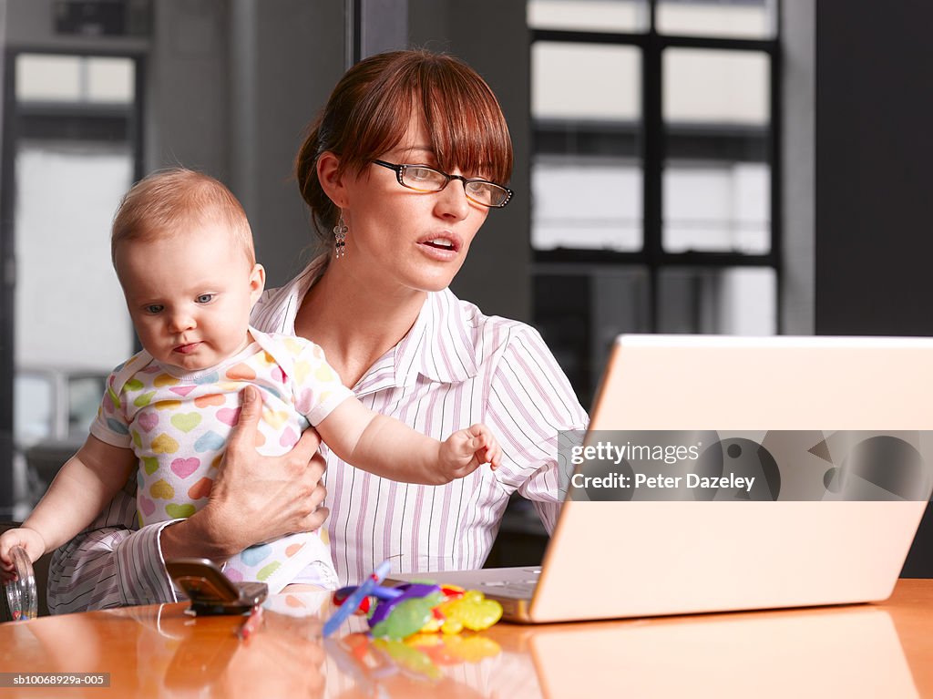 Mother with baby boy (6-11 months) working on laptop