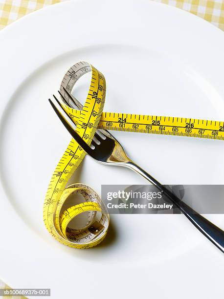 fork and tape measure on plate, close-up - fasten stock-fotos und bilder