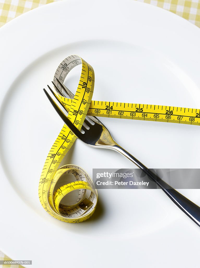Fork and tape measure on plate, close-up
