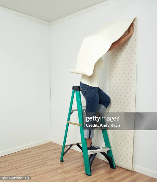 woman hanging wallpaper in room - careless stock pictures, royalty-free photos & images